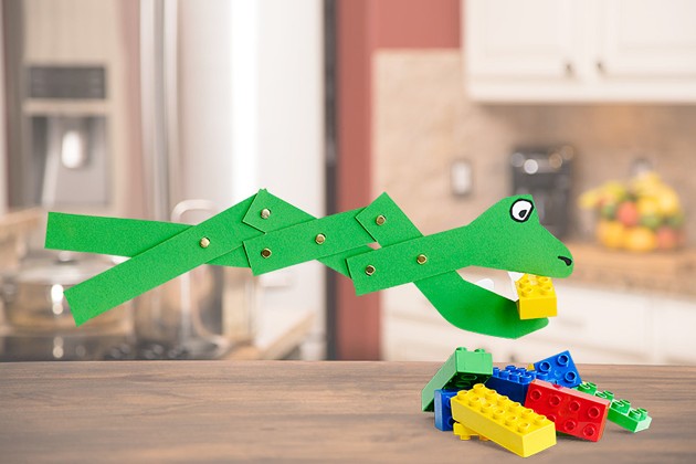 A hinged grabber toy eating a plastic building block.