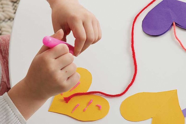 A child gluing heart shapes to a length of yarn.